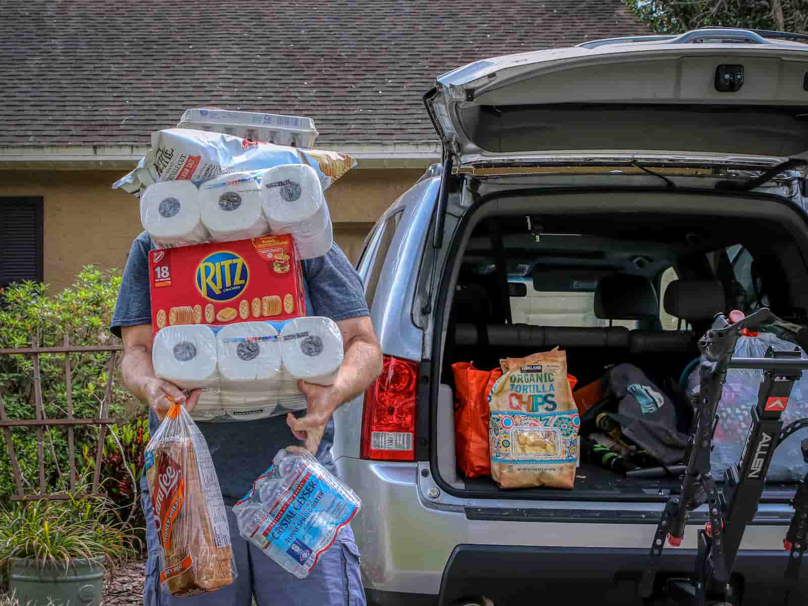 Persoon tilt veel boodschappen uit een auto